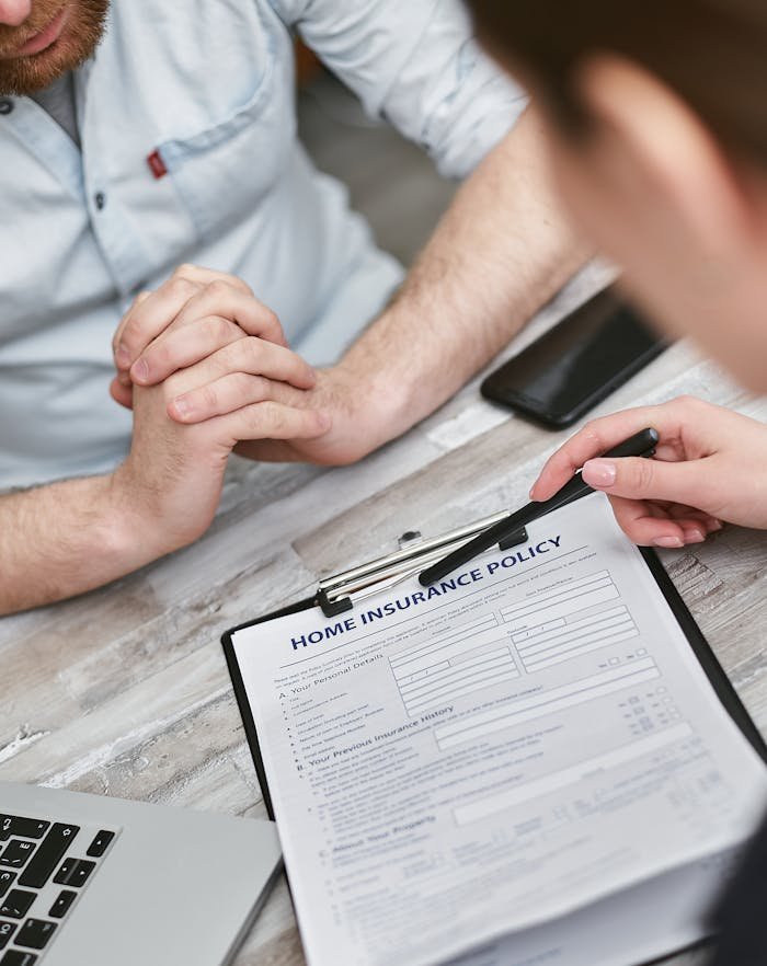 creative Two adults reviewing a home insurance policy document on a table with electronic devices.