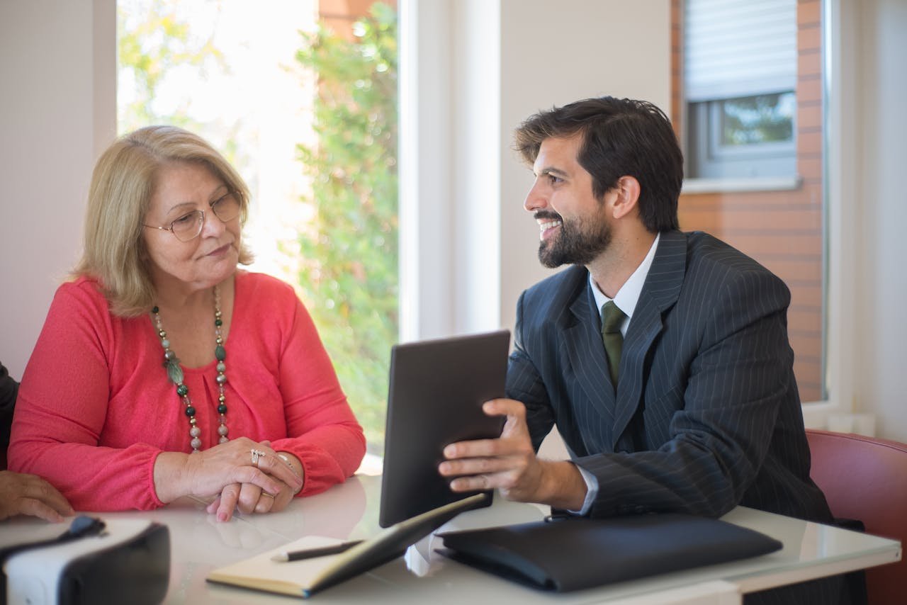 digital Elderly woman consulting with a realtor about a property deal in a cozy indoor setting.